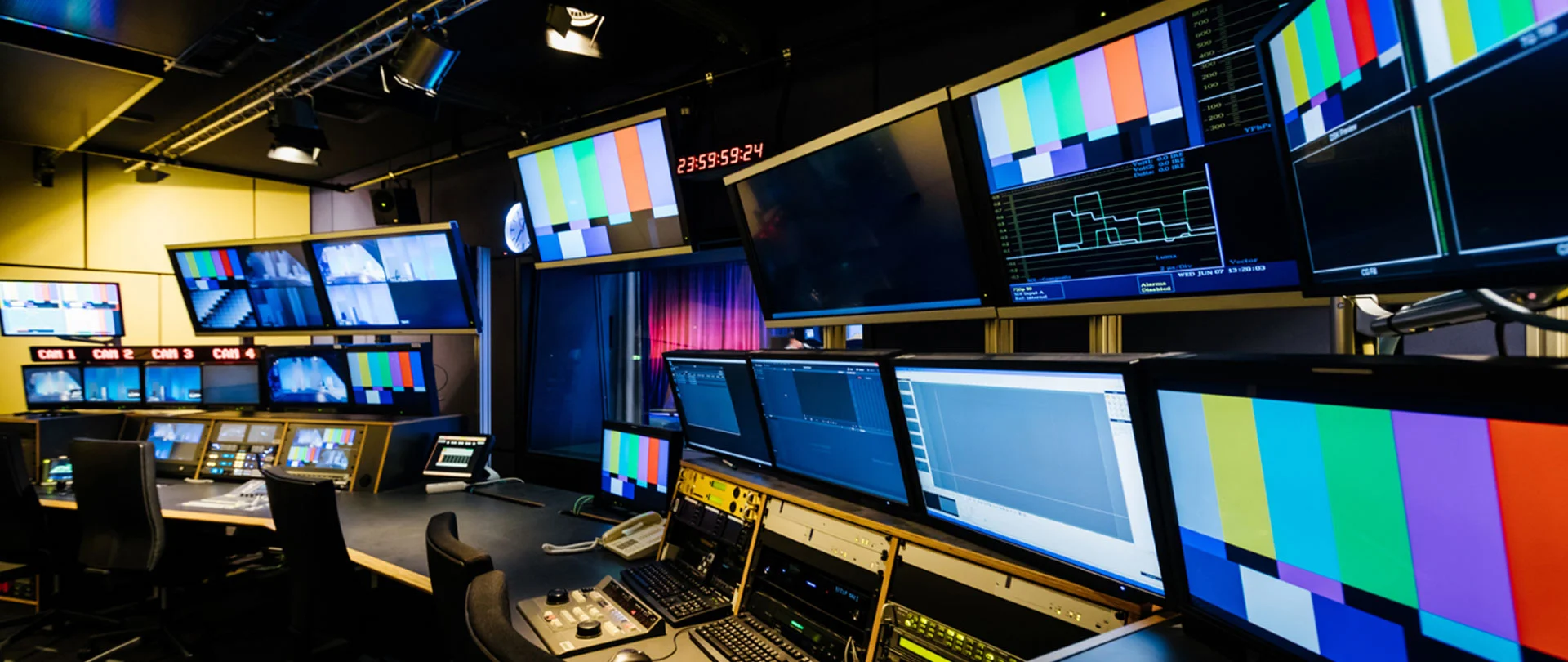 A comprehensive broadcast system integration setup featuring multiviewer, router rcp, intercom, program monitor, preview monitor, production desk furniture, light, waveform monitor, and camera preview monitor.