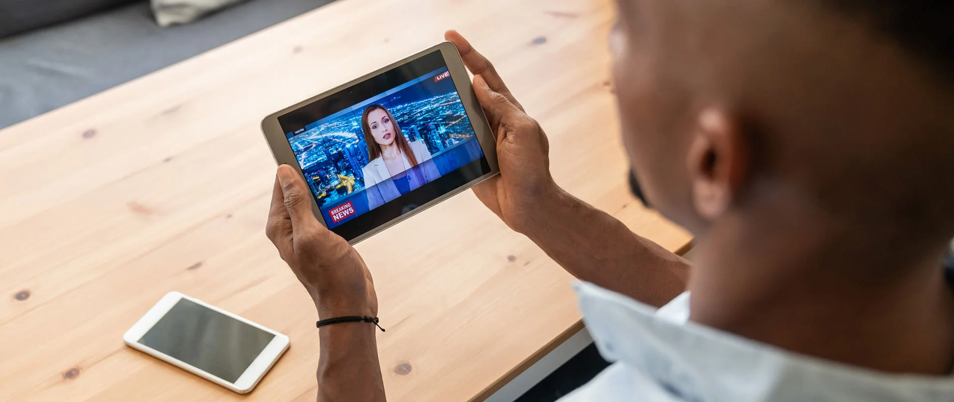 A man streaming videos on an OTT platform using his mobile device.