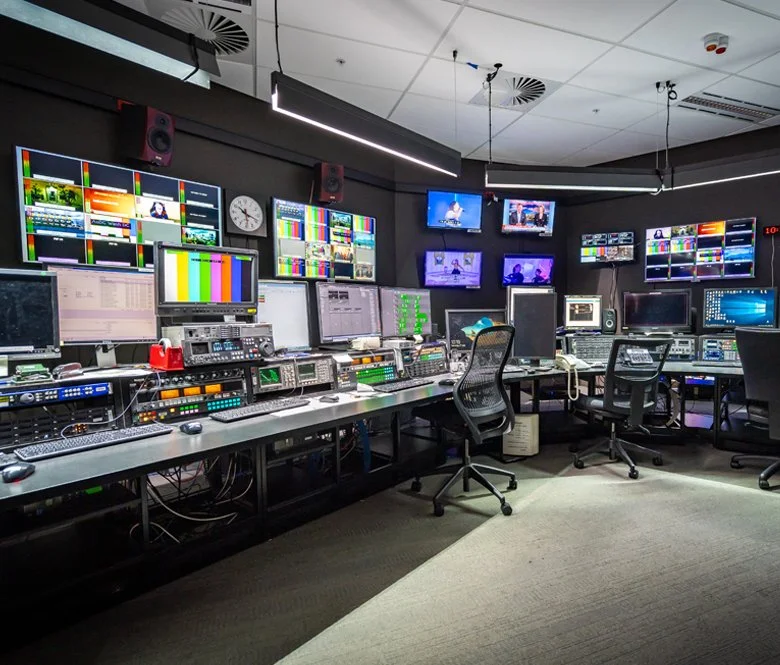 A comprehensive broadcast system setup featuring multiviewer, router rcp, intercom, program monitor, preview monitor, production desk furniture, light, waveform monitor, and camera preview monitor.